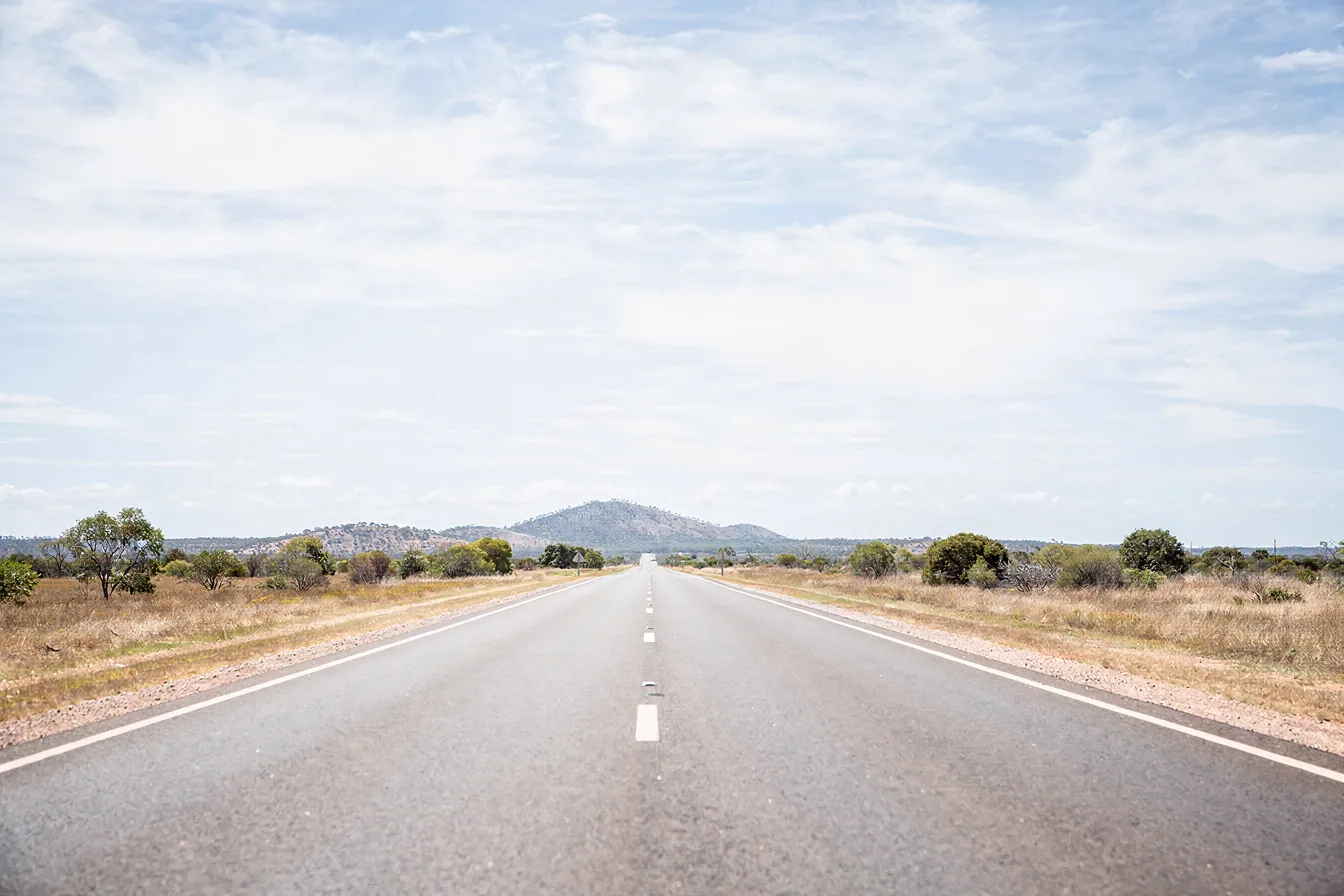 An empty regional road stretching toward distant hills.