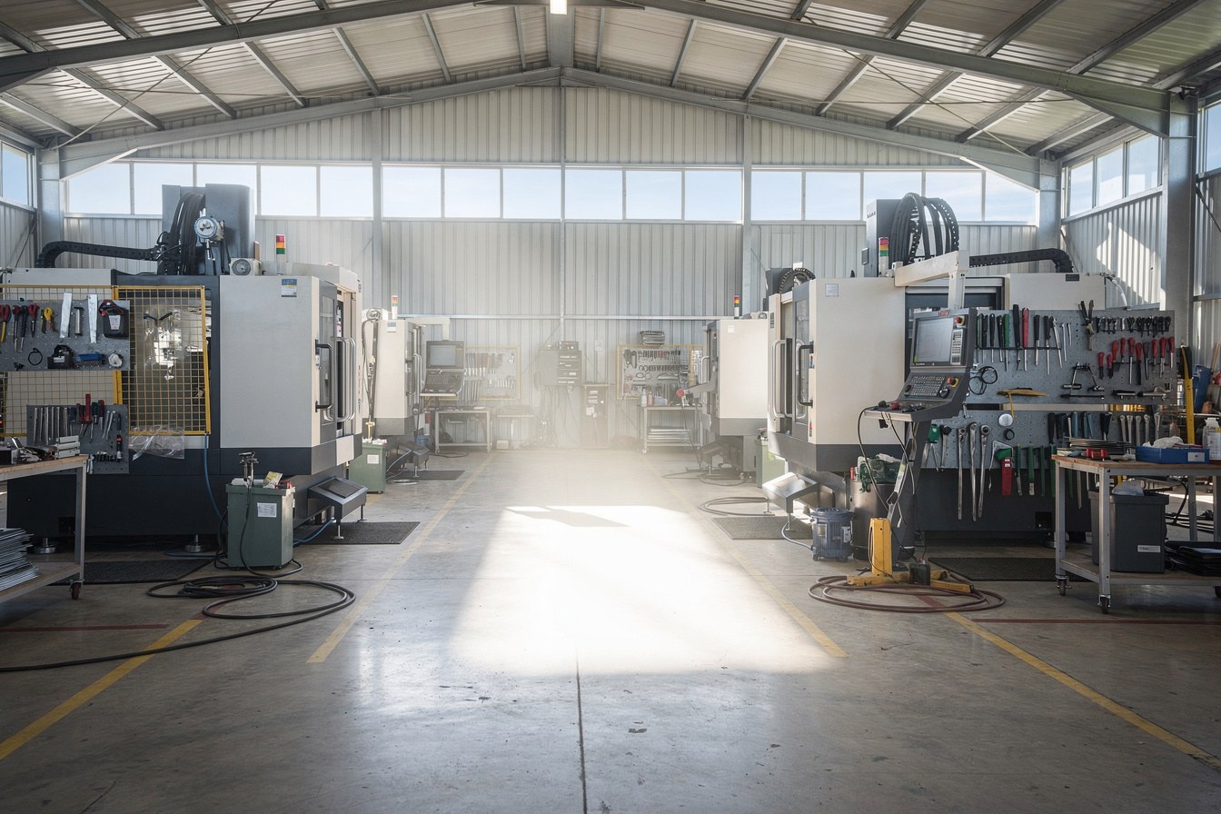 An empty gap on a factory production floor where a new machine would go, standing between two existing machines.